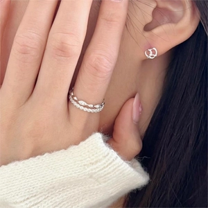 Detail of 925 sterling silver double-layer ring and bow earrings on model with soft lighting