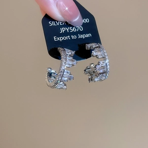 Close-up of 925 silver C-shaped earrings encrusted with sparkling zircon stones