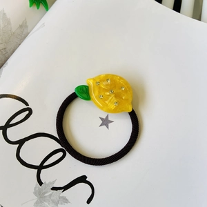 Detail of yellow acetate lemon hair tie with sparkling crystals on white background