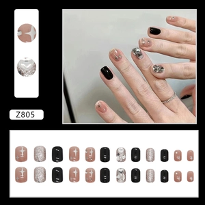 Short square press-on nails with black, silver glitter, and starburst heart designs