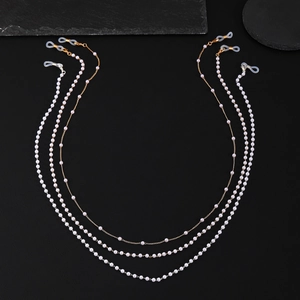 Détail de chaînes de lunettes en perles avec maillons dorés sur fond de pierre noire