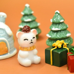Macro shot of a cute white resin bear with yellow scarf and miniature Christmas trees