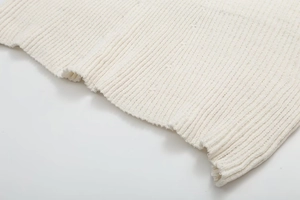 Detailed close-up of white ribbed knit fabric texture on sleeve cuffs and hemline