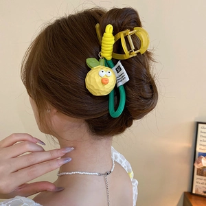 Close-up of a yellow cartoon fruit hair claw clip worn on a woman's ponytail