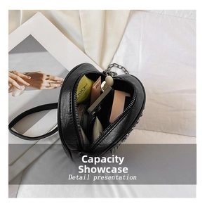 Detail presentation showing the capacity of this black heart-shaped leather crossbody bag