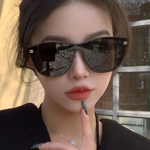 Fashionable oversized oval sunglasses with black frames and gold H-shaped temple accents