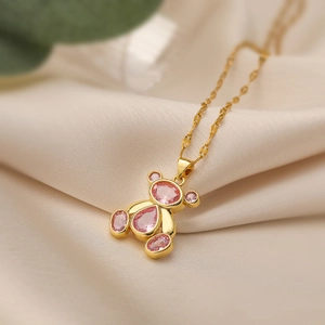 18K gold plated necklace with pink zircon bear pendant on soft beige silk background