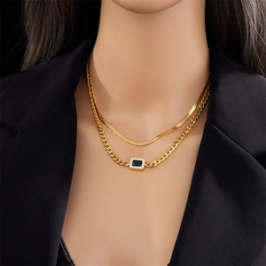 Gros plan d'un collier doré double épaisseur avec pendentif bleu sur un blazer noir