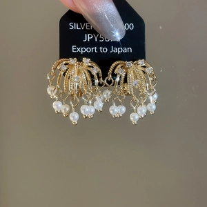 Detail view of 18k gold-plated zircon firework earrings with elegant dangling pearls