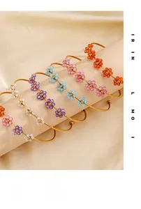 Detail of multicolor beaded flower bangles with gold finish on a jewelry display stand