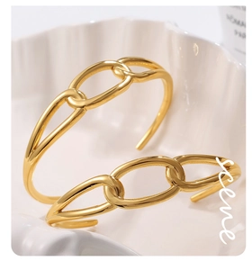 Detailed close-up of 18K gold-plated chain link open bracelets in a white shell dish
