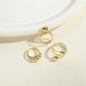 Three-piece gold adjustable metal ring set with smooth bead accents on textured surface