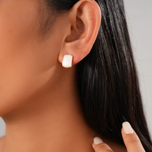 Detail of rectangular gold earrings with white enamel inlay worn by a model