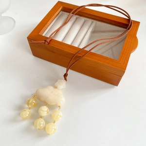 Close-up of leather cord necklace with white resin cloud and yellow bead pendants