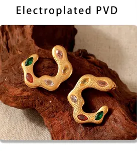 Detailed macro view of gold C-shaped twisted earrings with colorful zircon stones
