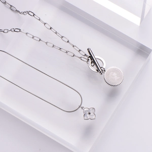 Silver layered necklace set with coin pendant and shell flower on acrylic stand
