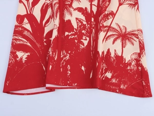 Detail view of tropical red palm tree print on ivory flowing summer dress fabric