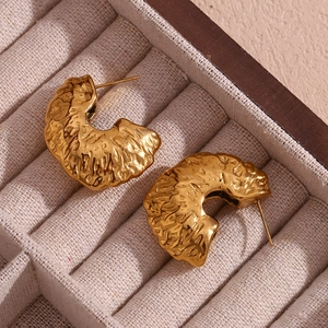 Macro shot of 18K gold plated C-shape earrings featuring a vintage hammered metal texture