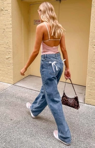 Detail of light blue wide-leg jeans featuring white ribbon bows on back pockets