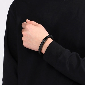 Close-up of a men's black braided leather bracelet with carbon fiber inlay on a male wrist