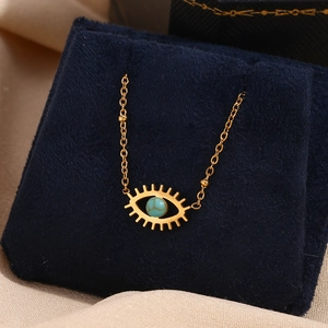 Macro shot of gold-plated evil eye pendant with turquoise stone on velvet cushion