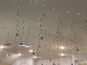 Metallic silver and rose gold spiral party streamers with star charms hanging from a ceiling