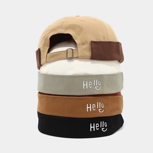 Détail de bonnets miki en coton empilés avec broderie hello et boucle en métal réglable