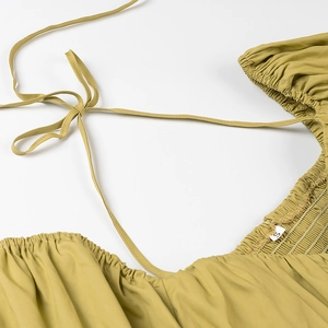 Detail view of mustard yellow halter top featuring adjustable neck ties and size S label