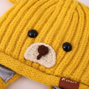 Detailaufnahme der gelben Bärenmütze mit weichem Baumwollfutter und KUKUJI-Lederlabel