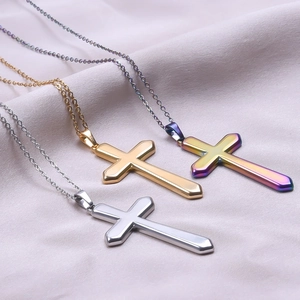 Polished stainless steel cross necklaces in gold, silver, and rainbow on pink silk fabric
