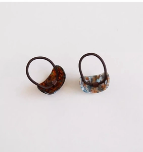 Detail of high-elasticity hair ties featuring curved acetate shell and marble patterns