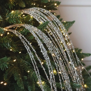 Sparkling silver sequin Christmas tassel ornament hanging on a festive tree with lights