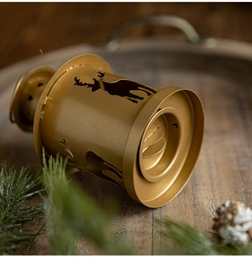 Detail of golden reindeer hollow metal candle holder on a rustic wooden tray