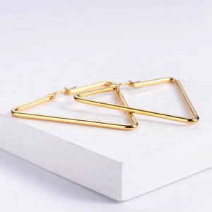 Polished 18K gold triangle hoop earrings in stainless steel on a minimalist stand