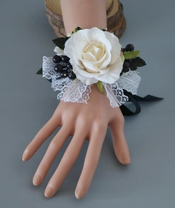 Corsage de poignet avec rose blanche, baies noires et dentelle pour le mariage