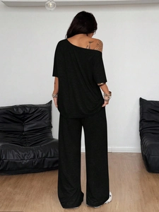 Detail view of black off-shoulder top and wide-leg trousers back profile