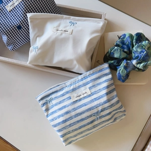 Close-up of small blue striped and gingham makeup bags with bow embroidery detail