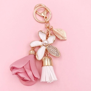 Close-up of floral keychain with white rhinestone petals, pink rosebud, and white tassel