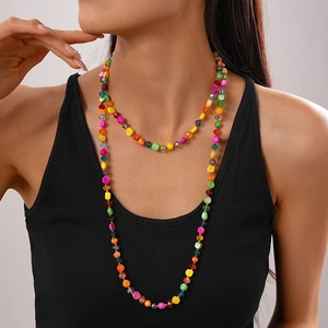 Detail of colorful irregular crystal beaded necklace layered on a woman's neck