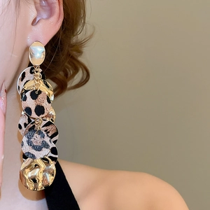 Détail de boucles d'oreilles léopard avec disques métalliques dorés sur un modèle