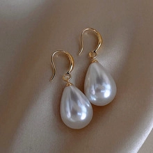 Vue macro de boucles d'oreilles perles vintage françaises avec crochets dorés sur soie