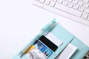 Close-up of light blue PU leather binder with multiple card slots and a matching pen