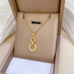 Detailed close-up of golden interlocking rings pendant with zircon stones in a jewelry box