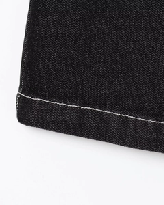 Detail of black denim fabric with white contrast stitching on sleeveless dress