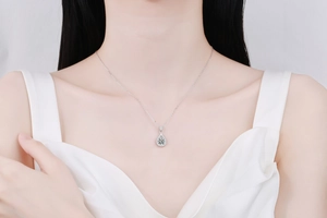 Close-up of a silver teardrop pendant necklace with moissanite stones on a female model