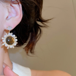 Close-up of vintage tiger eye stone earrings with pearls and crystals on a female model