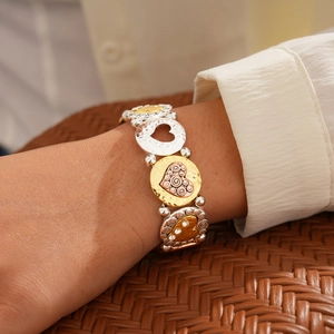 Détail du bracelet cœur tricolore avec breloques gaufrées et accents de diamants