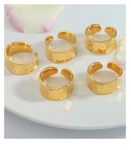 Detailed view of five gold-plated hammered rings on a white plate with floral accents