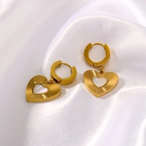 Golden heart earrings with white shell inlay on white silk fabric background