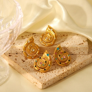 Close-up of golden spiral earrings set with colorful rhinestones on silk and stone